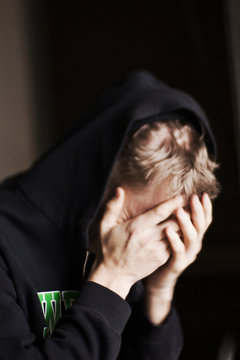 Man covering face with hands at home