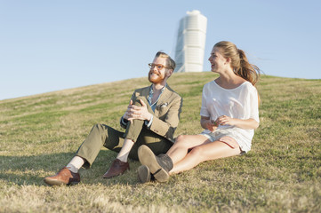 Happy couple sitting on grassy hill in city
