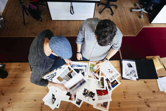High angle view of businessmen analyzing photographs at desk in office