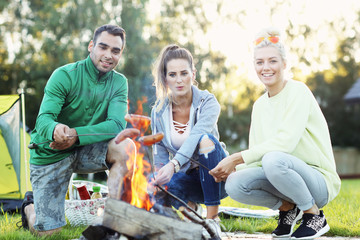 Naklejka na ściany i meble Group of friends preparing marshmallow on campfire