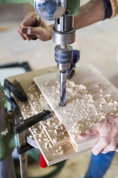 Cropped image of carpenter's hands drilling wood in workshop