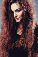 Portrait of attractive stylish woman in fur against grey background.