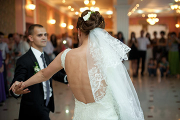 Naklejka premium A look from behind on the bride's open back while she dances wit