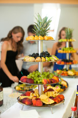 Ladies stand around the table with fruits