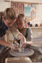 Female potter assisting girl