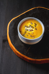 Fresh homemade carrot soup with pumpkin seeds and sour cream in