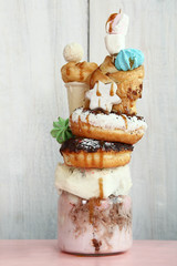 milkshake with doughnuts and other sweets in a jar on  wooden background