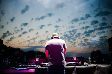 Club, disco DJ playing and mixing music for crowd of happy people. Nightlife, concert lights, flares