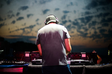 Club, disco DJ playing and mixing music for crowd of happy people. Nightlife, concert lights, flares