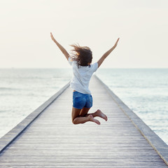 Fototapeta na wymiar Back view of jumping girl on the pier