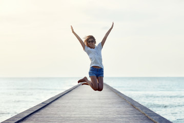 Fototapeta Happy jumping girl on the pier obraz