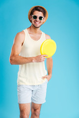 Happy young man in hat and sunglasses holding frisbee disk