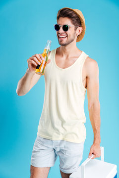Cheerful young man holding cooler bag and drinking beer