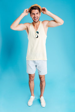 Full length of happy young man in shorts and hat