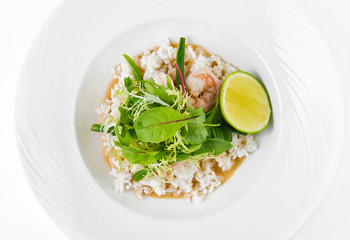 Prawns in coconut curry teriyaki, string beans and lime on a plate on a white background, top view