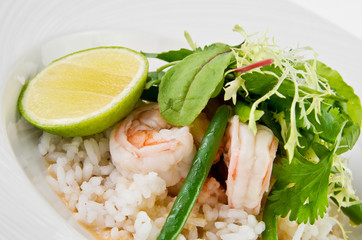 Prawns in coconut curry teriyaki, string beans and lime on a plate on a white background, closeup