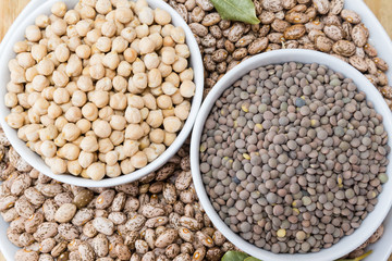 beans, chickpeas and lentils in porcelain bowls on a wooden table
