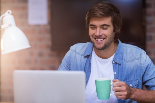 Businessman having coffee while working on laptop