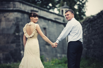 Fototapeta na wymiar Bride and groom look over their shoulders walking around an old