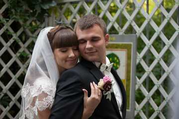 Bride clothes her eyes leaning to the groom while standing on th