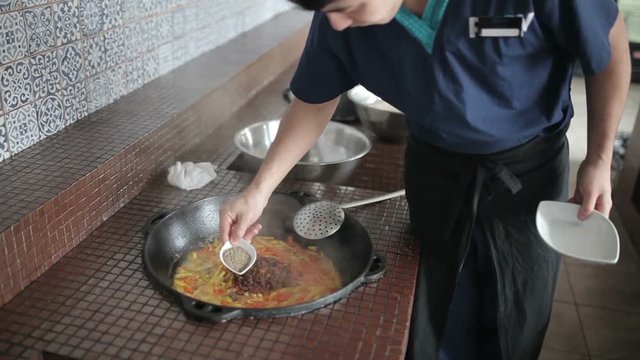 Cook adding spices into the pot.