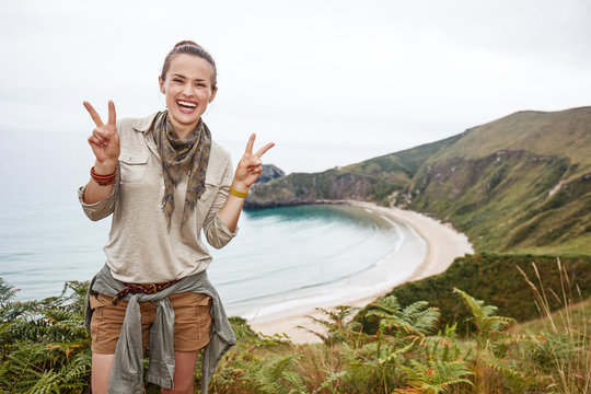 woman hiker showing victory in front of ocean view landscape