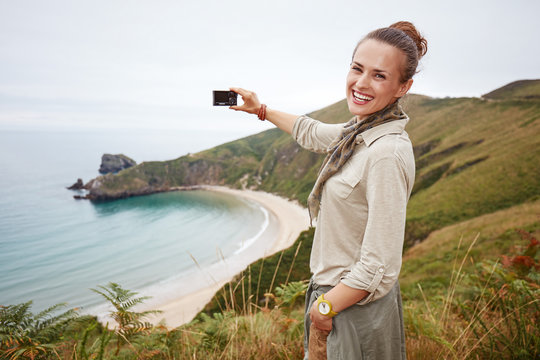 woman hiker taking photo in front of ocean view landscape