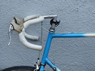 Klassisches blaues Rennrad mit weiß umwickeltem Rennlenker vor blaugrauer Fassade im Hansavieertel...