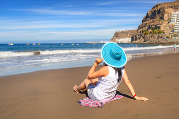Woman in hat enjoying sun holidays on the beach of Gran Canaria