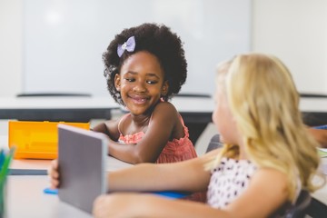 Schoolgirls interacting while studying in classroom