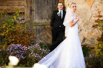 Gorgeous bride in a dress with long train walks before a groom