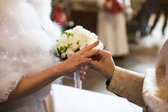 Priest puts a wedding ring on a bride's hands during the ceremon