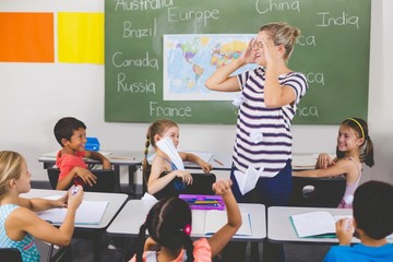 School kids throwing paper balls on teacher