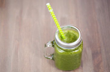 A green smoothie in a mason jar on wooden background