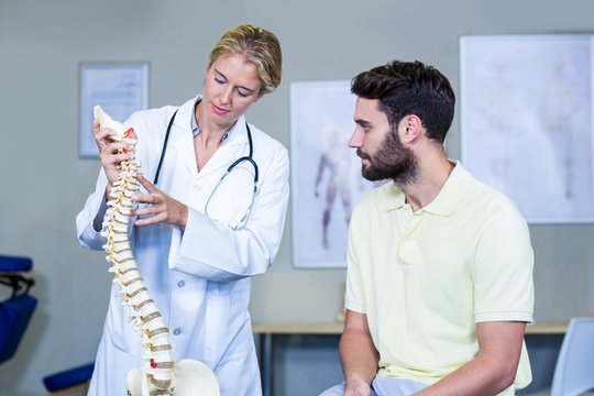 Physiotherapist explaining the spine model to patient