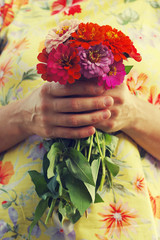 Bouquet of bright summer flowers in the girl's hands in a yellow dress. Festive bouquet