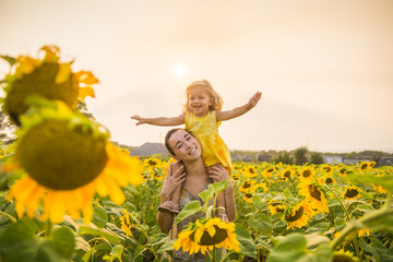 Mom and daughter in the field of sunflowers