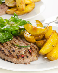 Beef burger patty with the roasted potato, side salad and spices on wh