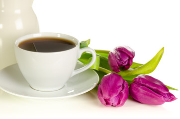 Fototapeta na wymiar White cup of coffee with bunch of purple tulips on white backgro