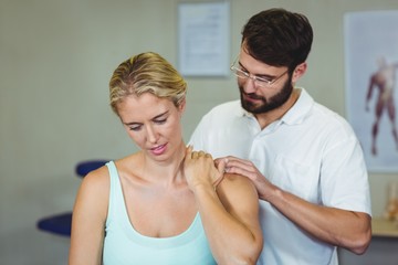 Fototapeta premium Male physiotherapist giving neck massage to female patient