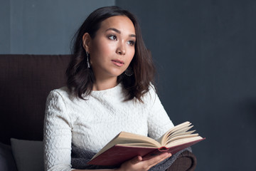 young,beautiful girl wrapped in warm plaid blanket reading book