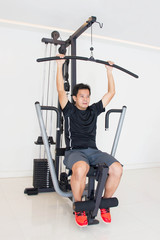 Fototapeta na wymiar Asian Man Doing Exercise On Fitness Machine In Gym