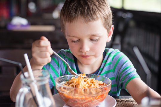 Little 7 years old boy child eating spaghetti bolognese
