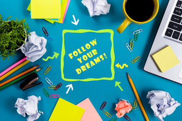 Follow your dreams. Office table desk with supplies, white blank note pad, cup, pen, pc, crumpled...