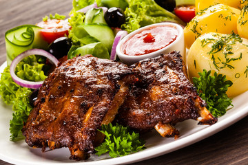 Grilled ribs, French fries and vegetables on white background 