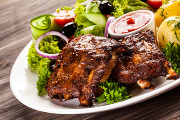 Grilled ribs, French fries and vegetables on white background 