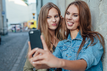 Two young girl taking selfie on the street.