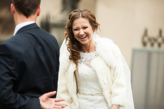 Smiling bride in white fur coat walks to a groom