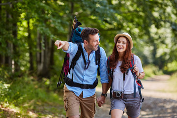 Couple hiking together in woods with backpacks