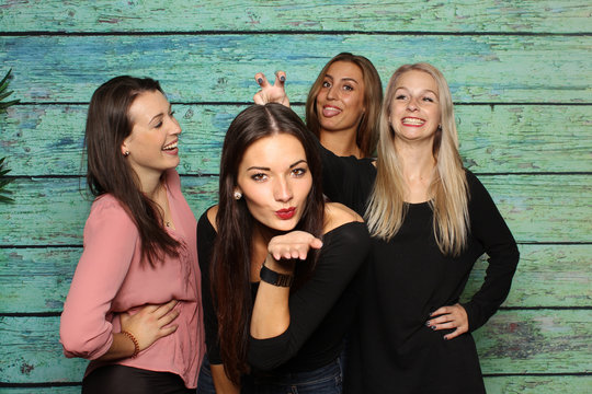 4 hübsche Mädchen albern vor einer Fotobox herum - Lachen und Luftküsse mit Photobooth